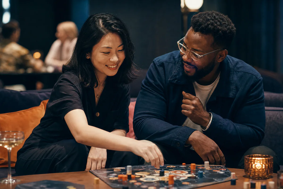A couple talks and laughs over a board game in a relaxed lounge.