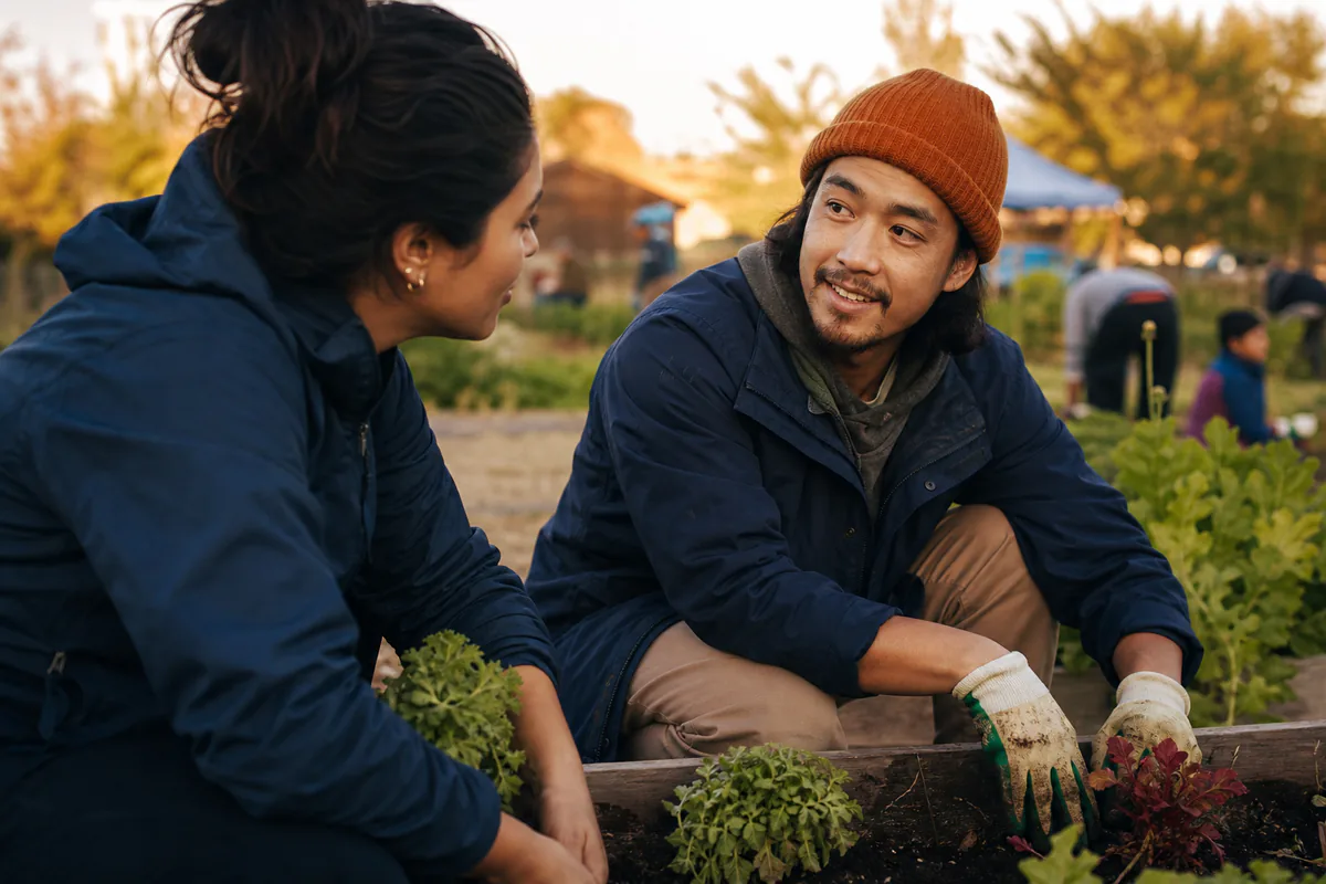 A couple talks while tending plants in a community garden.