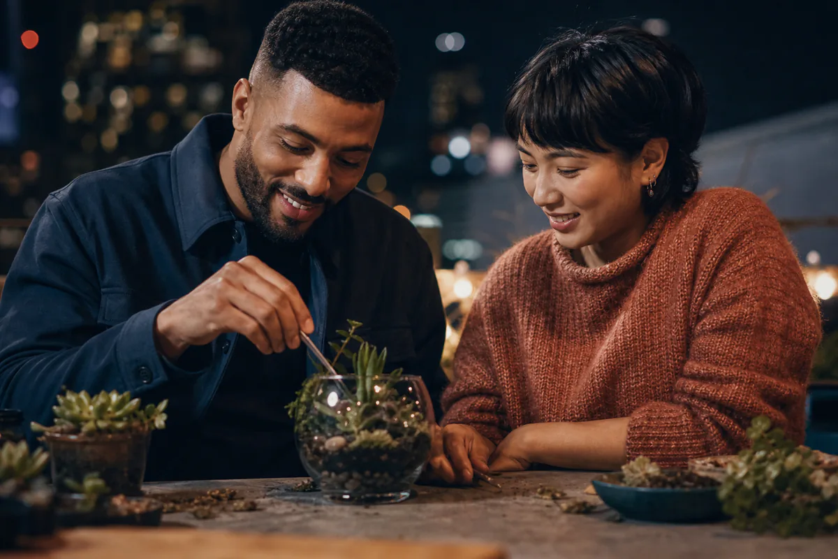 A couple builds a small terrarium together at an evening workshop.